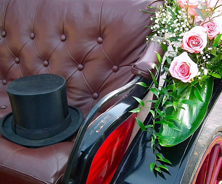 Hochzeitskutsche mit Blumenschmuck und Zylinder für eine romantische Hochzeitsfahrt in der Eifel.